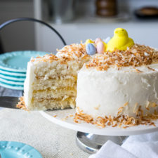 A white layer cake with white icing and a slice removed from it