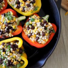 A close up of the peppers stuffed with couscous, and beans in a skillet