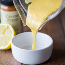 A bowl on a table with sauce being poured into it