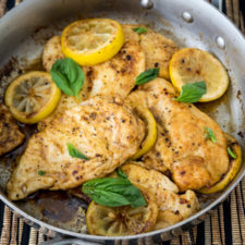 A pan of food with chicken breasts and lemon slices