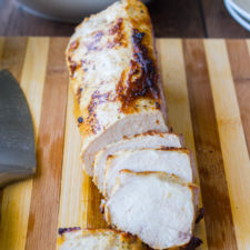 A loaf of bread on a wooden table, with many slices already cut