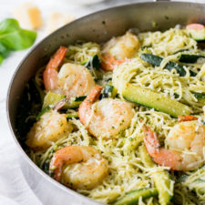 Skillet on a table with shrimp pesto, pasta and veggies