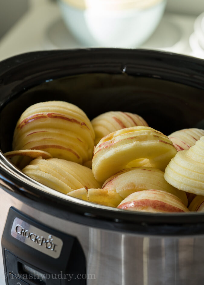 Place the peeled apples into the slow cooker and add water.