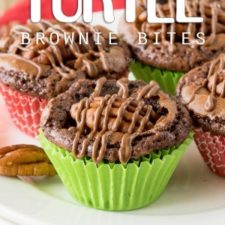 Mini chocolate brownies on a plate topped with a nut and drizzled melted chocolate