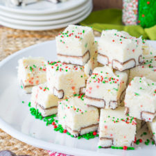 Small squares of white fudge on a plate, with red and green sprinkles on top