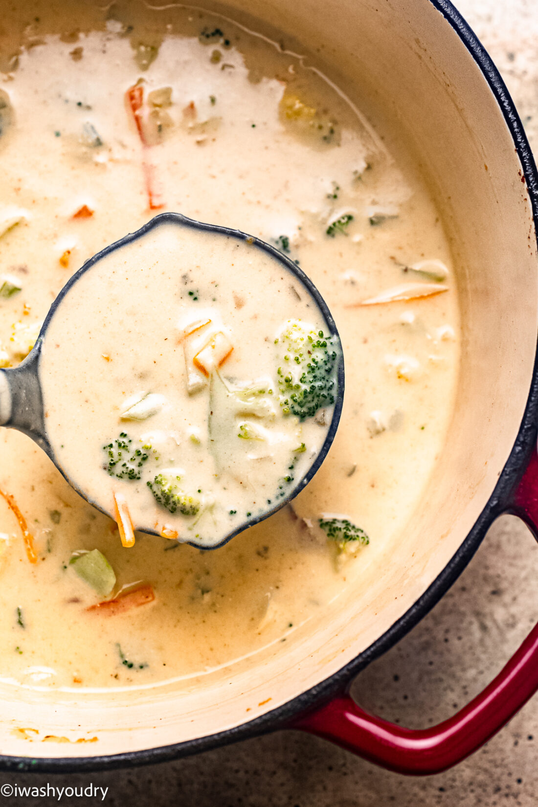 black ladle with broccoli cheese soup in large pot.