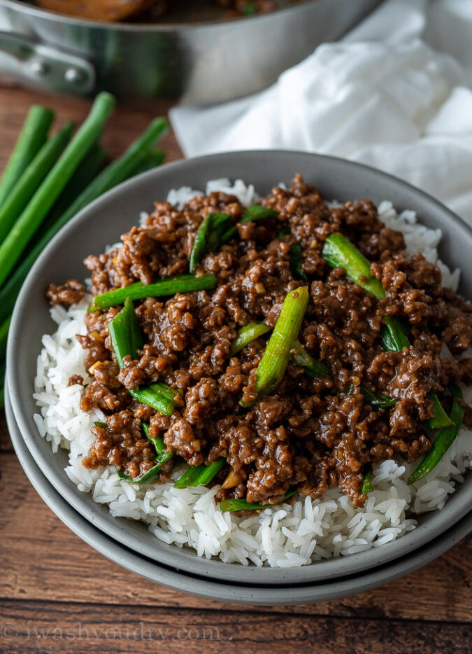 bowl of rice topped with ground beef and sauce with green onions.