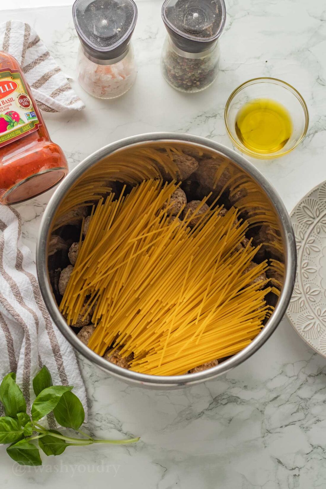 Dry uncooked spaghetti noodles on layer of meatballs in instant pot. 