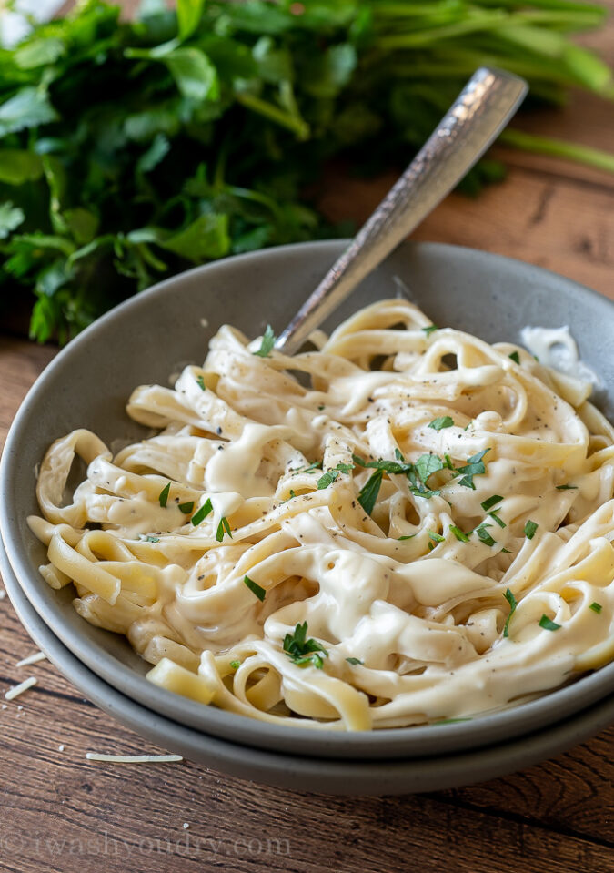 homemade Alfredo Sauce over a bowl of fresh fettuccini noodles