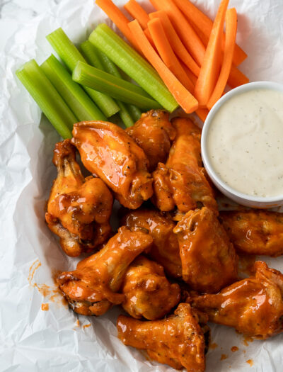 Saucy Buffalo Wings in basket with celery and carrots and a side of ranch dressing