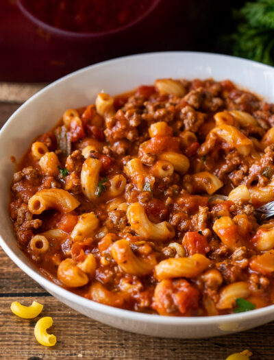 Tender macaroni pasta in a beef and tomato sauce in a white bowl.