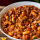 Tender macaroni pasta in a beef and tomato sauce in a white bowl.