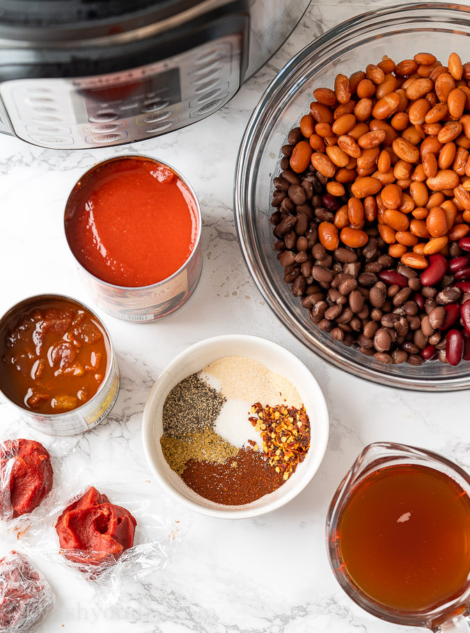 Ingredients needed for Chili laid out on marble table top.