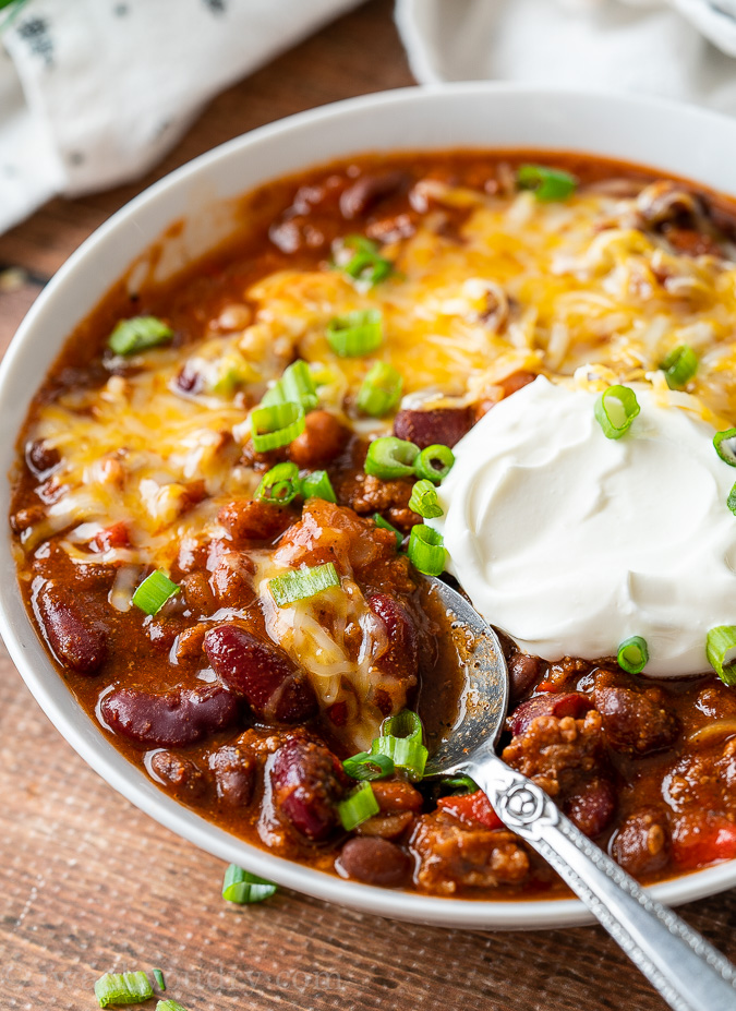 Close up of bowl with chili, spoon inside bowl.