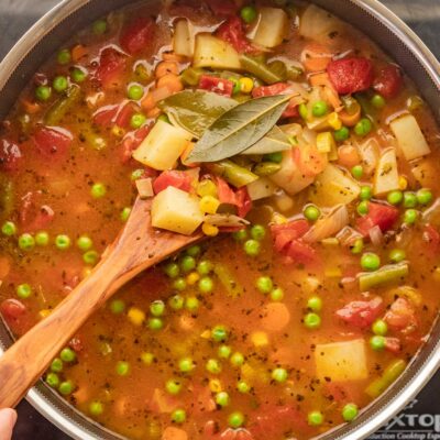 Large pot filled with vegetable soup and ladle.