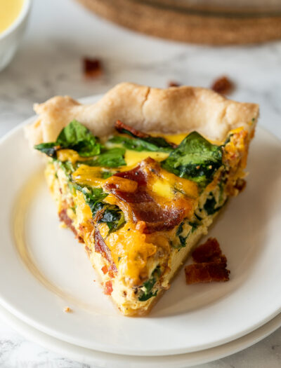 Bacon Cheddar Quiche Recipe : slice of quiche on white plate.