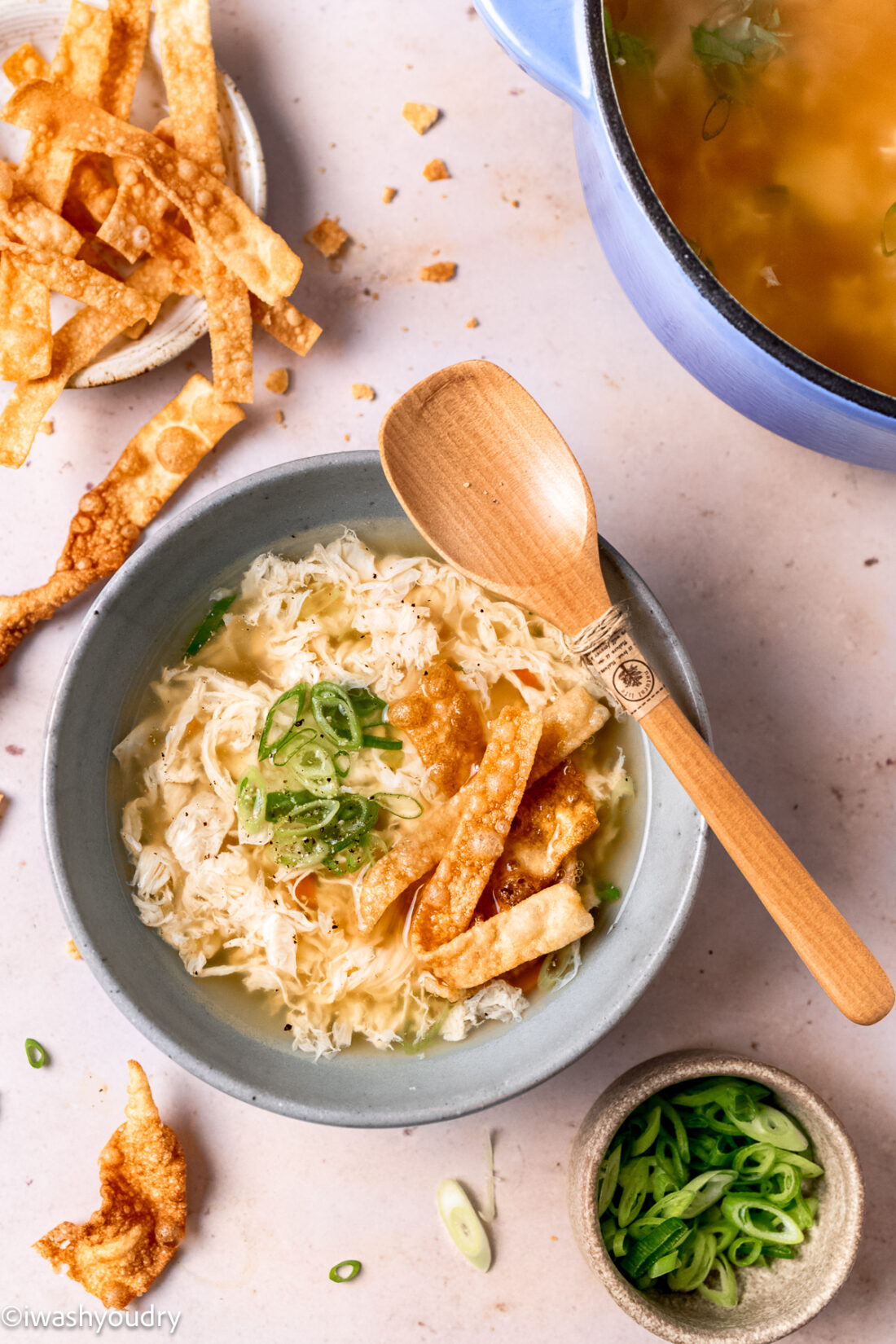 Cooked egg drop soup with wooden spoon resting on bowl. 