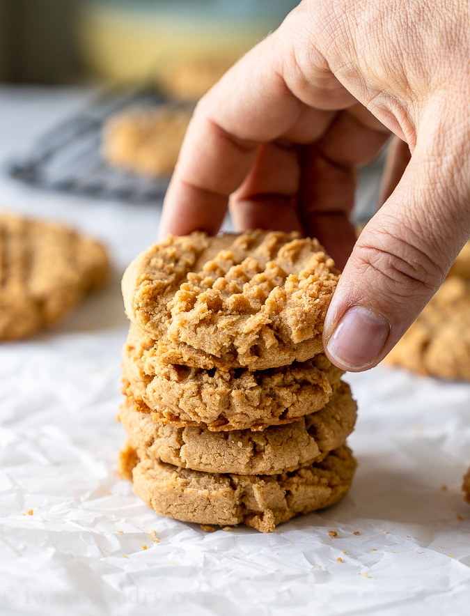 A stack of peanut butter cookies with a hand reaching down to grab one.