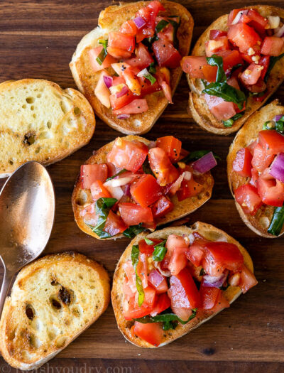 Slices of toasted baguette with fresh tomato bruschetta on top.