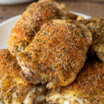 Oven Roasted Chicken Thighs on a white plate with seasoning on top.