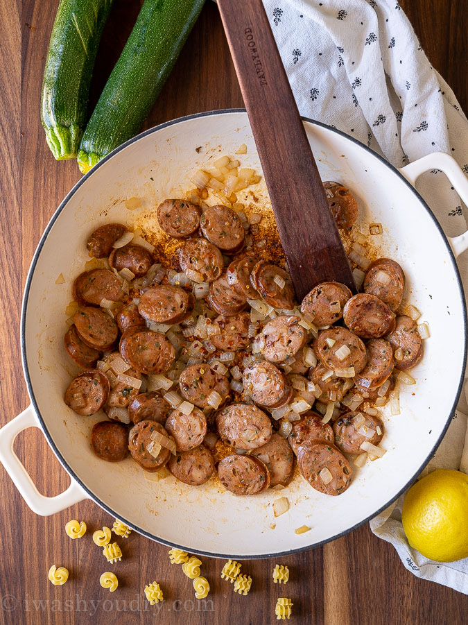 Sautéd chicken sausages and diced onion in pan