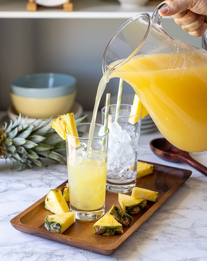 Pouring lemonade into a cup filled with ice.