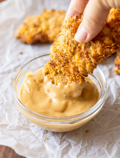 Dipping crispy chicken tenders in chick fil a sauce.