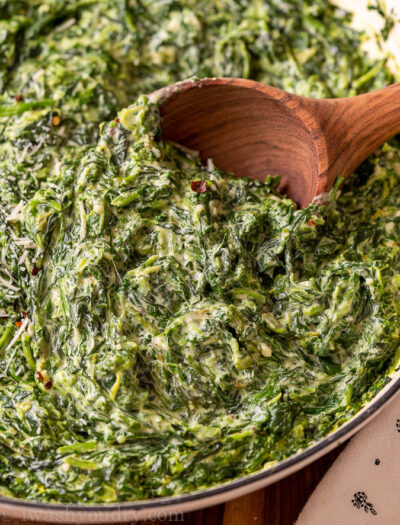 closeup of spinach in a pan with wooden spoon