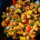 wok filled with sweet and sour chicken and vegetables