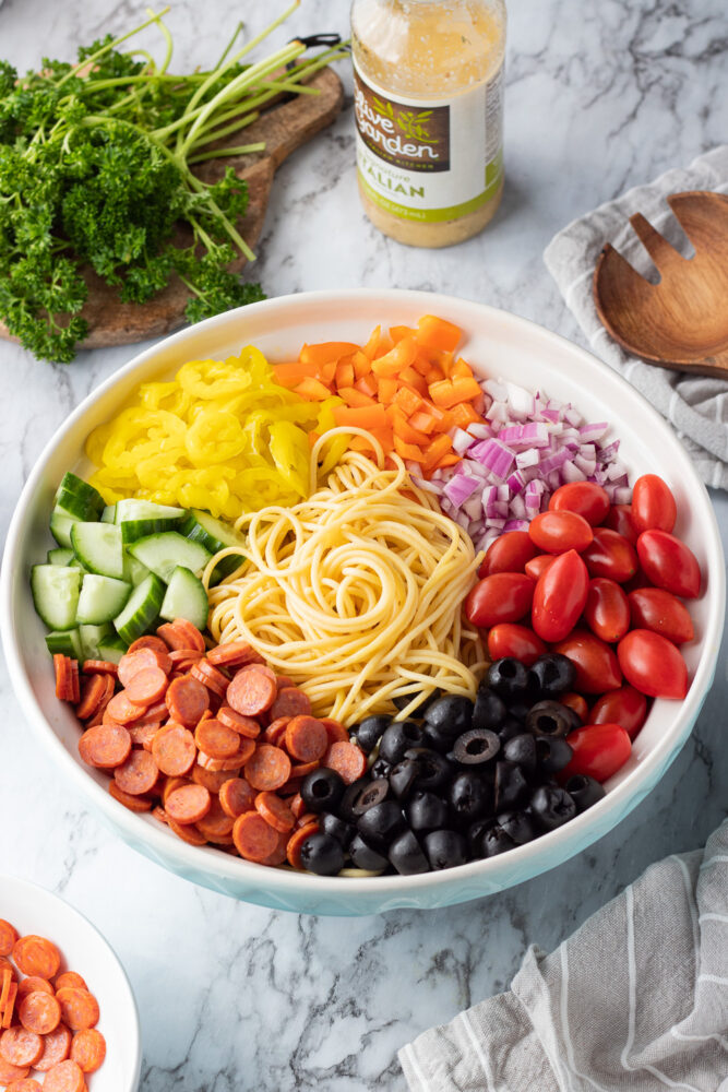 ingredients in a bowl for spaghetti pasta salad with parsley and italian dressing. 