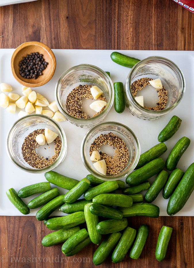 preparing mason jars with spices and cucumbers