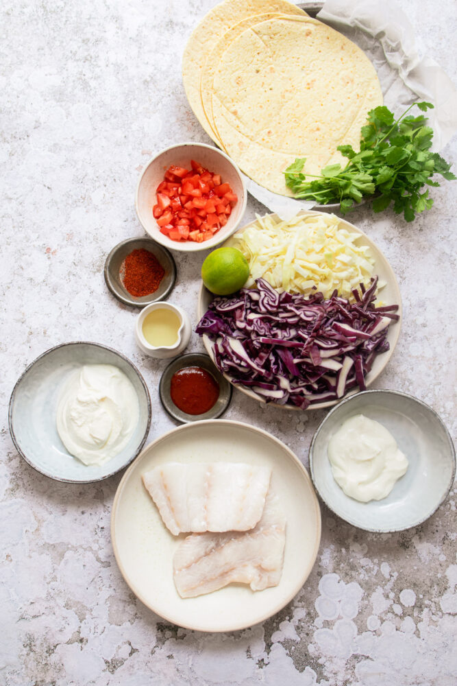 Ingredients for grilled fish tacos on surface