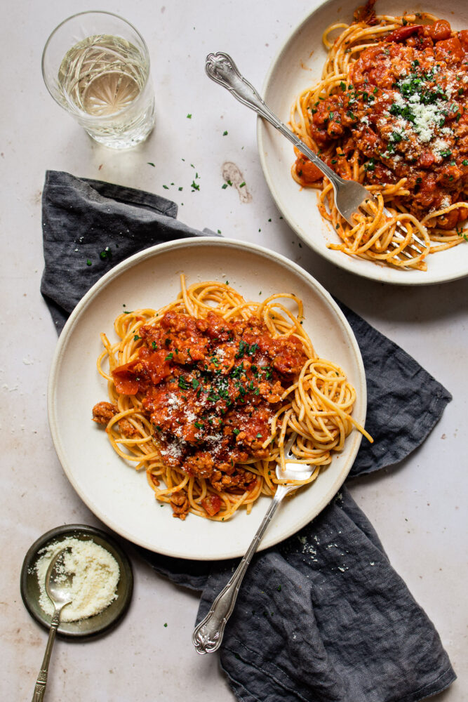 two plates of pasta with forks