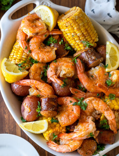 white dish filled with shrimp, potatoes, corn and sausage