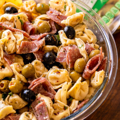 olive tortellini pasta and salami in bowl with dressing