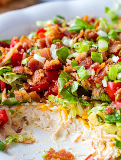 ceram cheese, cheddar cheese, avocado, lettuce, tomato and bacon in a white dish.