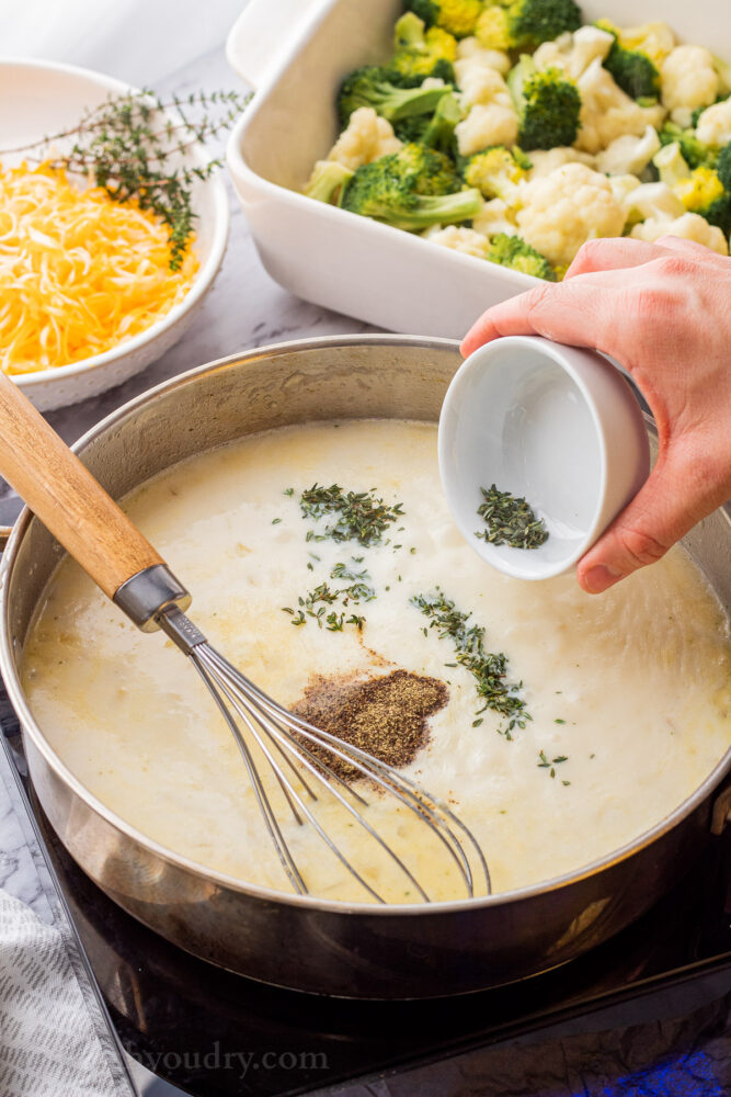 Pouring thyme into frying pan of sauce. 