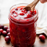 Sweet cranberry sauce in mason jar with spoon