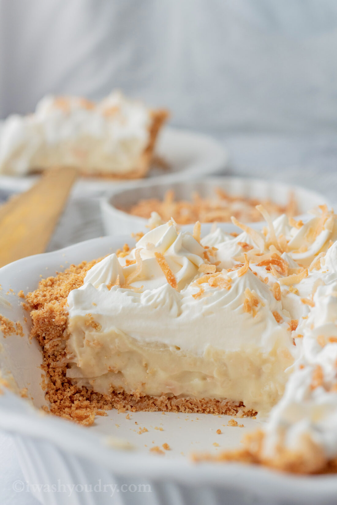 Sliced coconut cream pie in white pan.