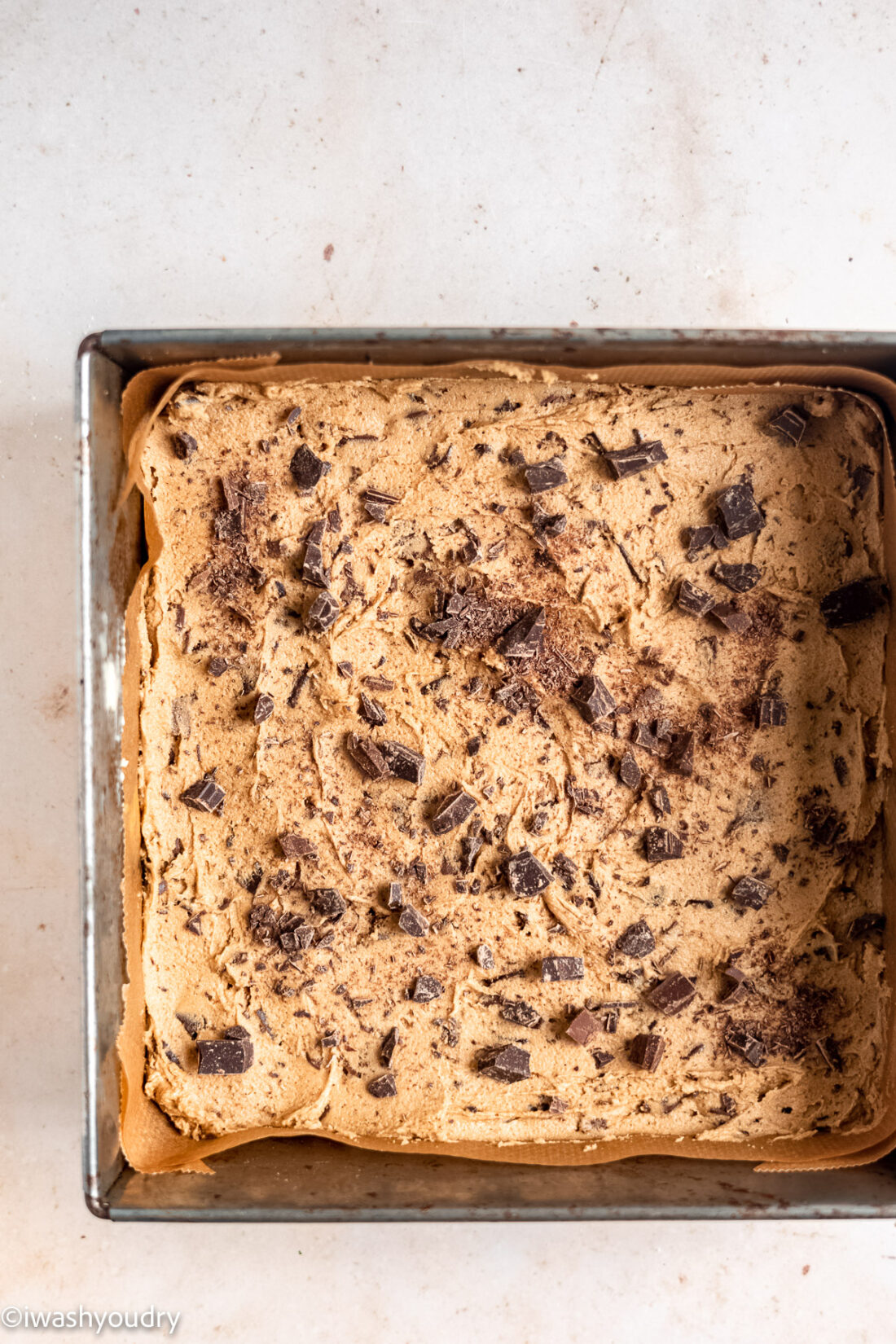 Raw chocolate chip blondie batter in square metal pan. 