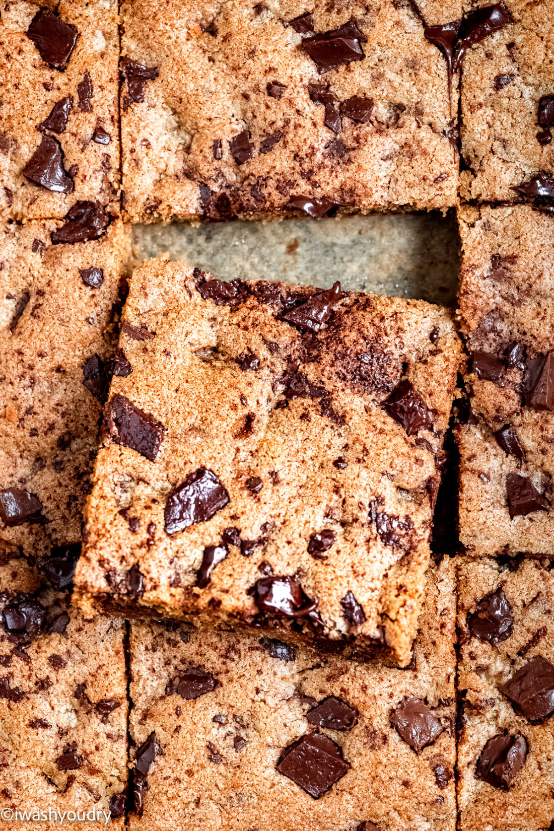 Slice of baked chocolate chip blondie resting on other baked slices. 