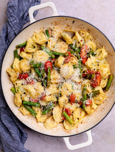 cheesy tortellini in pan with asparagus and tomatoes