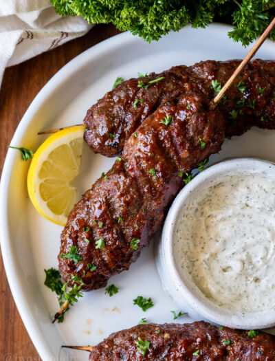 plate of meatloaf skewers with cream sauce and lemon.