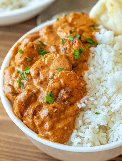 Cooked Shrimp Tikka Masala in white bowl with rice and naan.