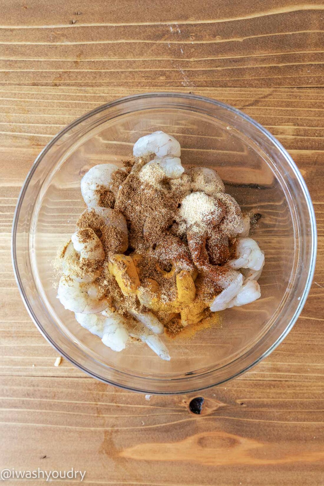 Raw Shrimp with tikka masala spices in glass bowl. 