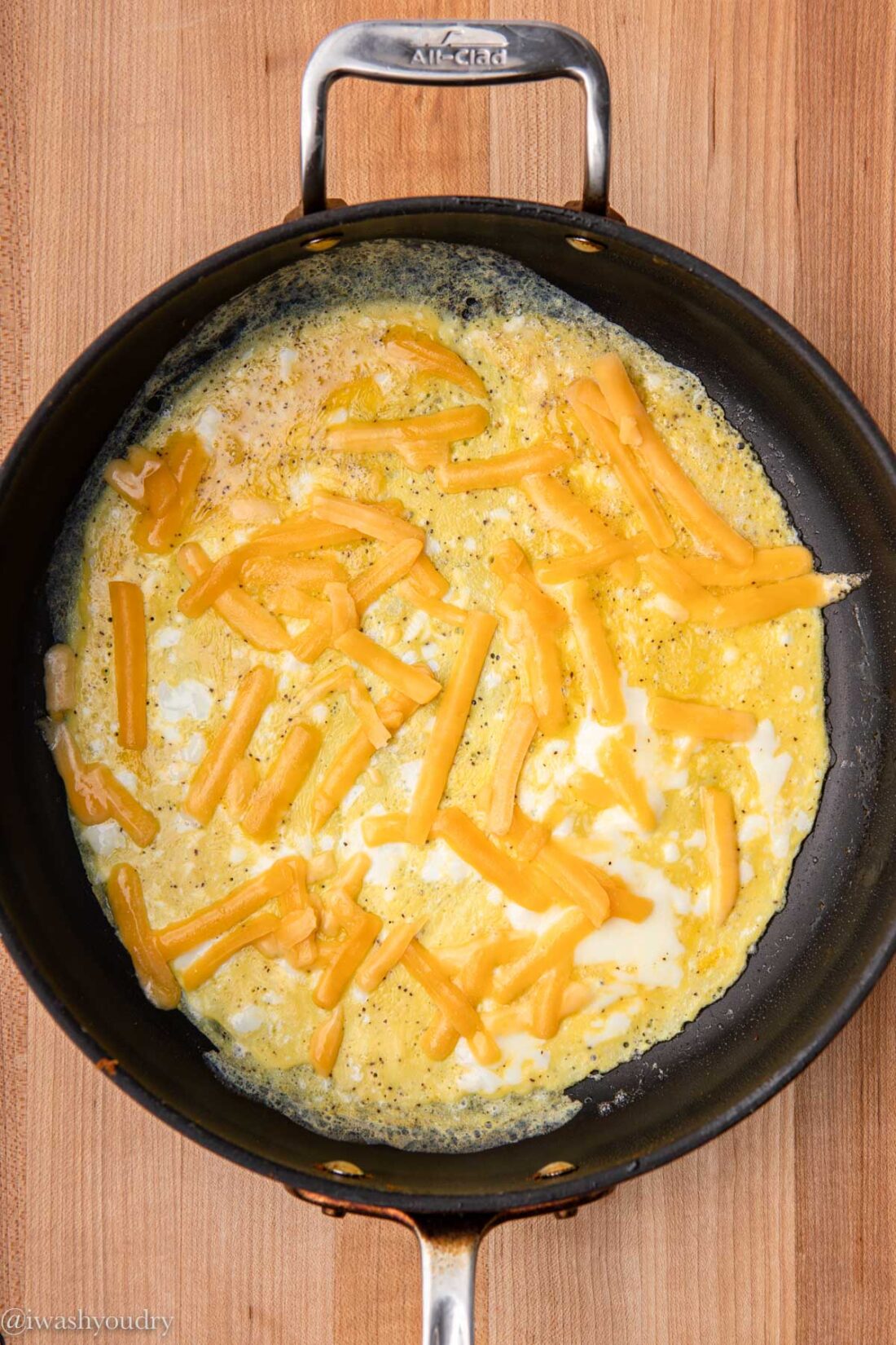 Cooking eggs with cheese in frying pan.