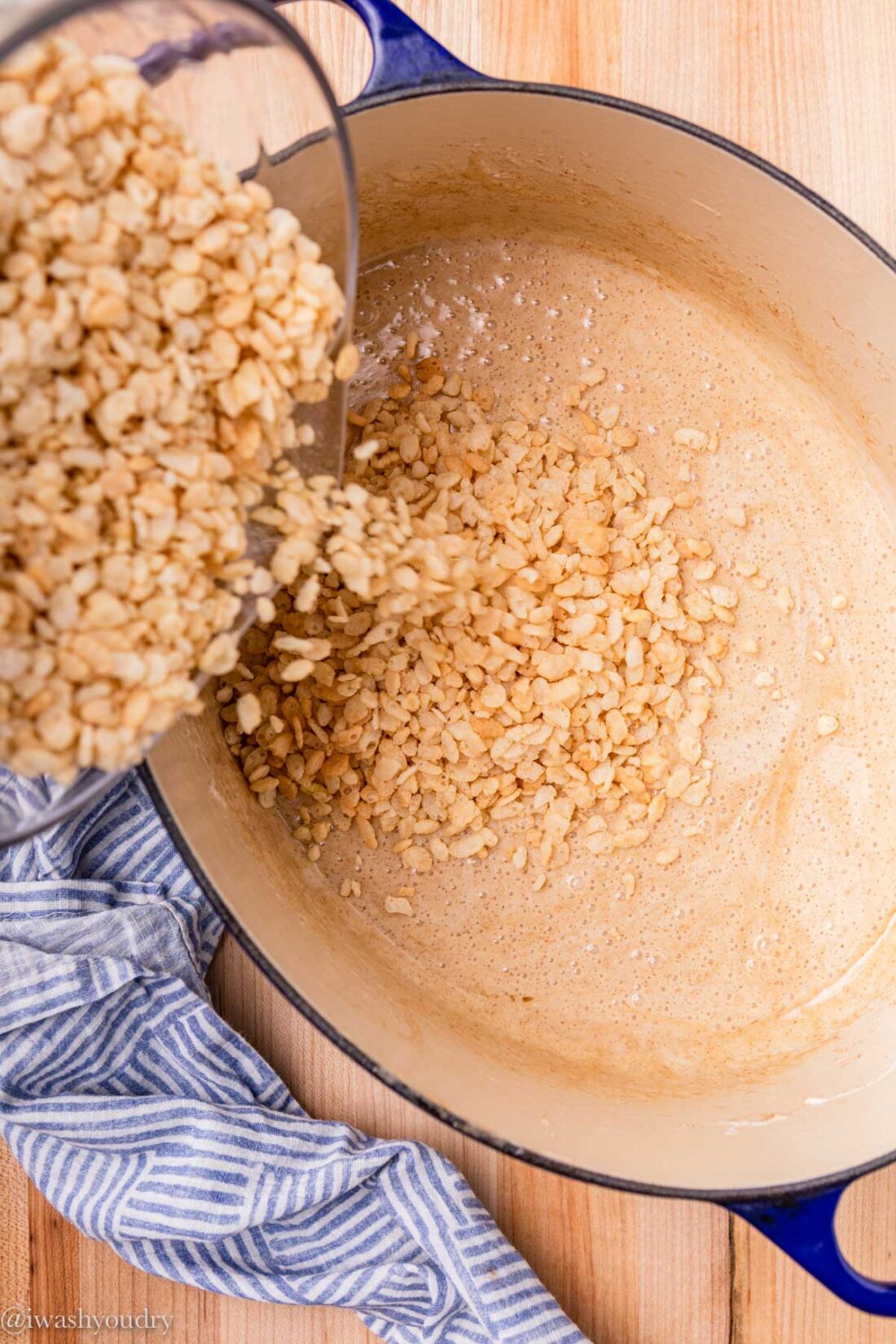 adding rice cereal to marshmallow sauce in pot.