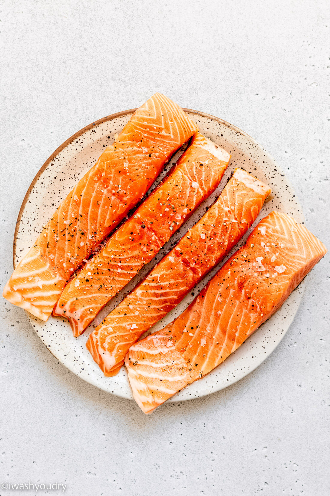 Raw lemon garlic salmon on white plate. 