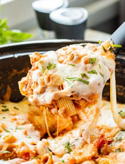 Spoonful of cooked slow cooker baked ziti above crock pot.