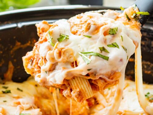 Spoonful of cooked slow cooker baked ziti above crock pot.